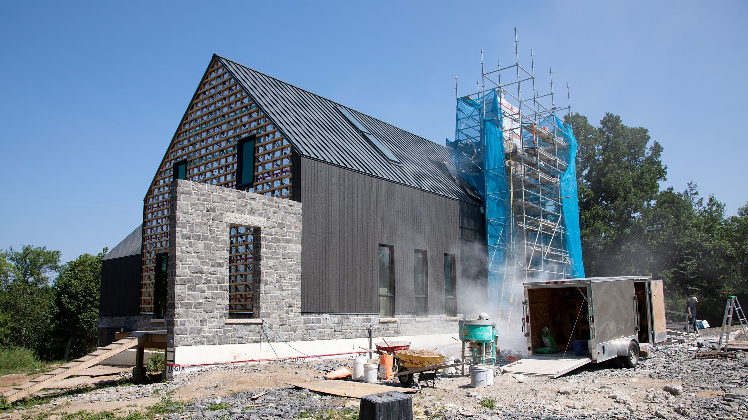 Dust swirls around the scaffolded 28ft. high chimney as masons work to clad it in stone. On the left the window wall is complete