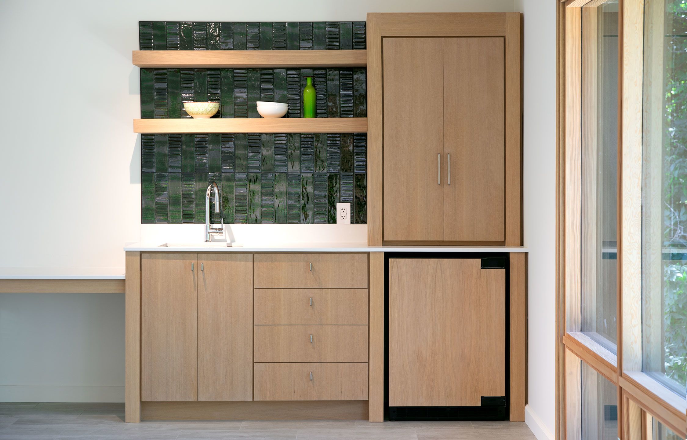 Custom kitchen has a green glazed tile backsplash.