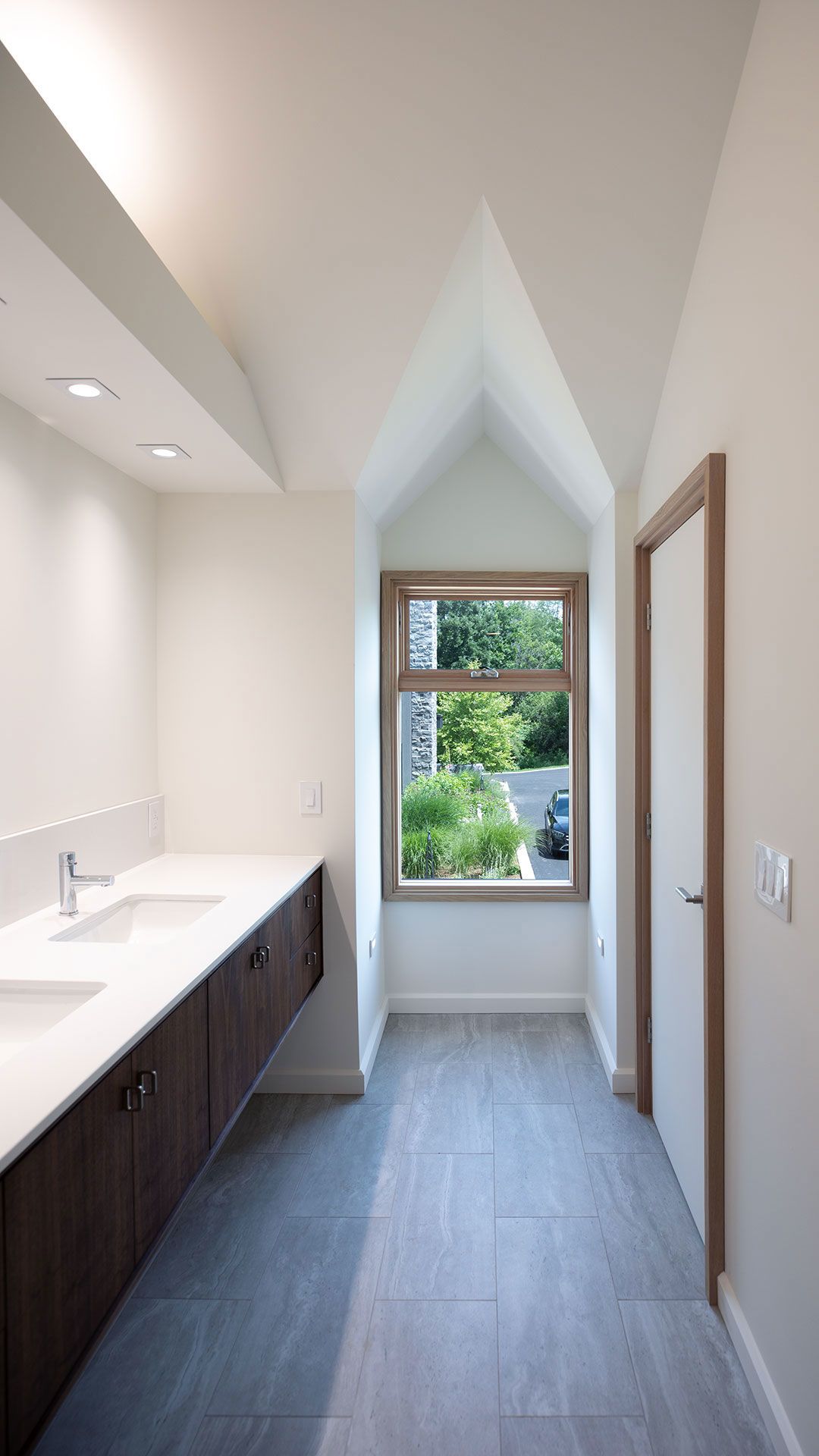 view of bathrrom dormer window with peaked detail and views of the house and driveway beyond.