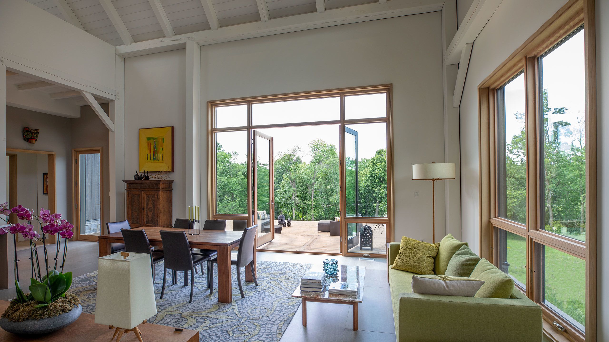 WWide view of Sitting_Dining area with 10 foot high double doors opening out to the deck and Napanee River views