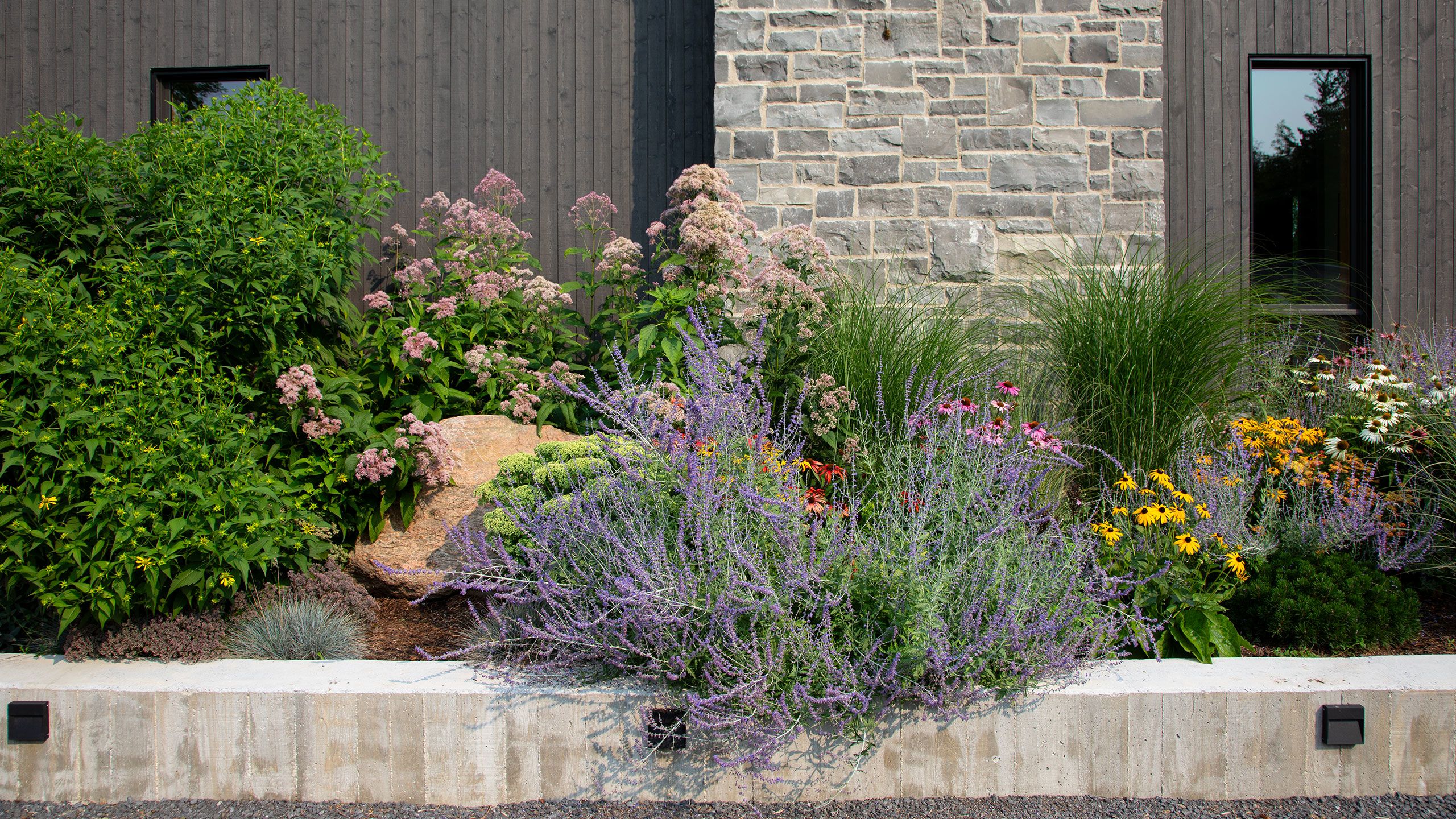 Garden with wood textured retaining wall, and limestone chimney.
